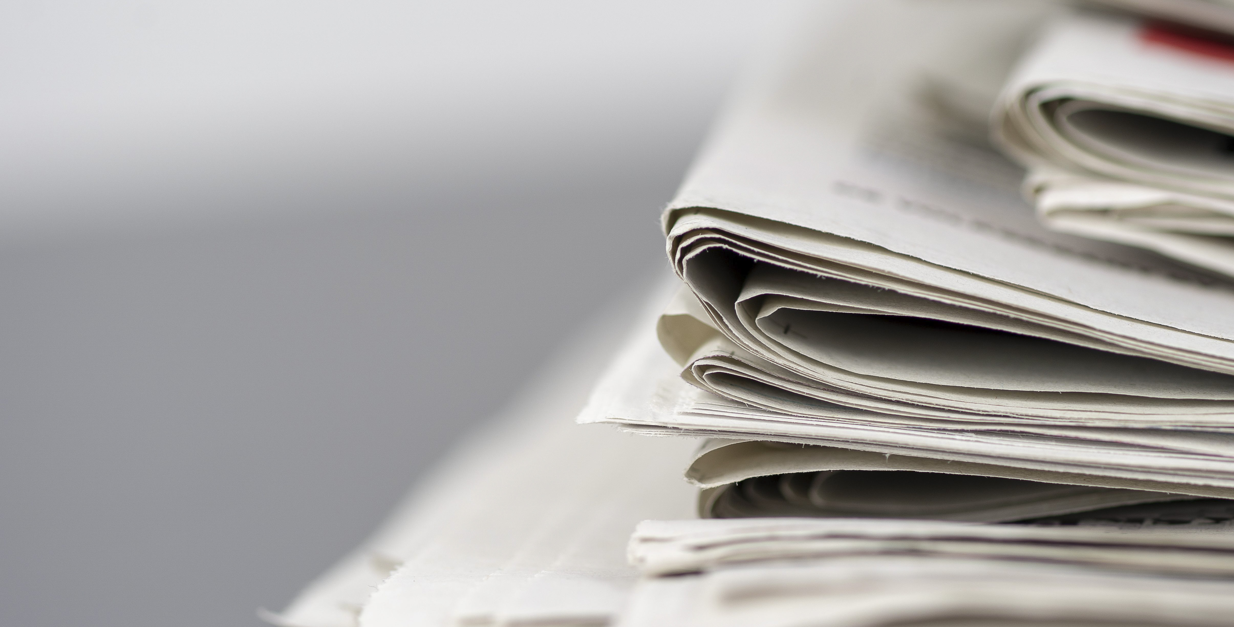 Folded newspapers stacked against a blurred background
